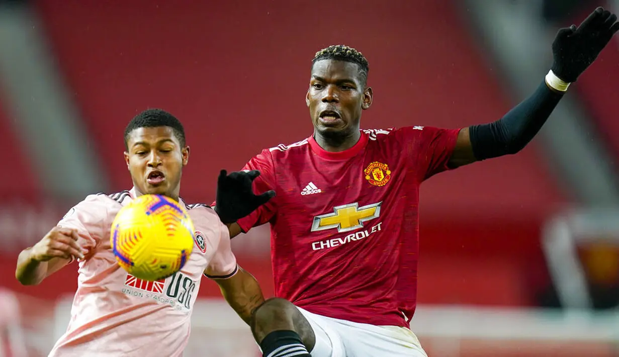 Gelandang Manchester United, Paul Pogba, berebut bola dengan pemain Sheffield United, Ethan Ampadu, pada laga Liga Inggris di Stadion Old Trafford,  Kamis (28/1/2021). MU takluk dengan  skor 1-2. (AP/Tim Keeton,Pool)