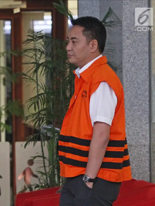 Tersangka anggota DPR Fayakhun Andriadi mengenakan rompi tahanan berjalan meninggalkan gedung KPK usai diperiksa, Jakarta, Rabu (28/3). Fayakhun tidak berkomentar dan hanya tersenyum saat ditanya soal penahanannya tersebut. (Liputan6.com/Herman Zakharia)