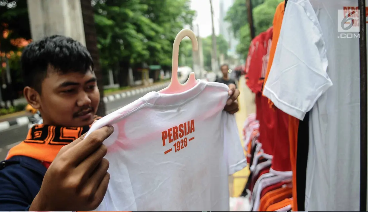 Seorang suporter Persija melihat kaos di kawasan Senayan, Jakarta, Minggu (9/12). Pedagang memanfaatkan momen pertandingan Persija Jakarta yang akan bertanding melawan Mitra Kukar. (Liputan6.com/Faizal Fanani)