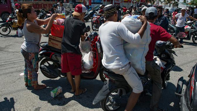 Warga membawa kebutuhan pokok menggunakan motor setelah menjarah toko swalayan menyusul gempa dan tsunami di Palu, Sulawesi Tengah, Minggu (30/9). Warga terpaksa mengambil karena mereka juga membutuhkan makanan dan air bersih. (AFP PHOTO/BAY ISMOYO)