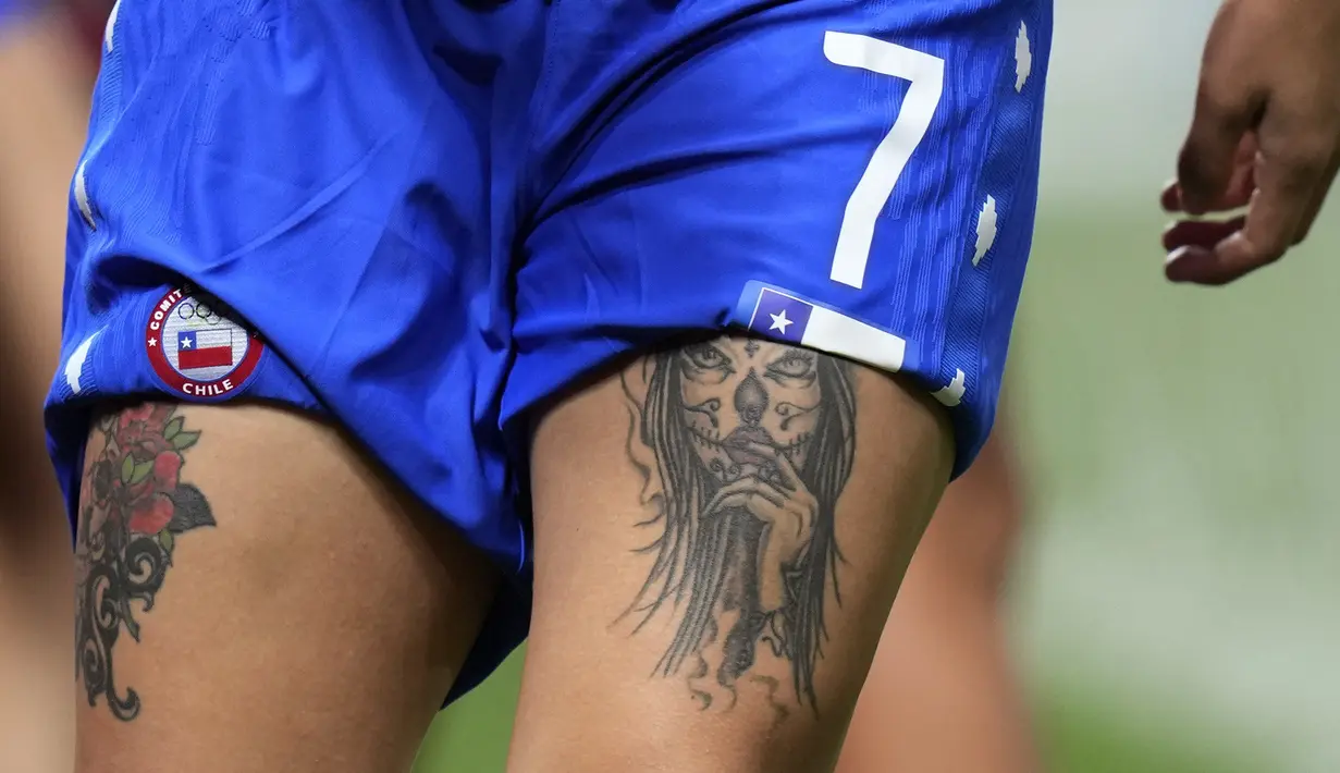 Tato di paha pesepak bola Chile, Yenny Acuna saat pemanasan sebelum pertandingan sepak bola wanita melawan Kanada di Olimpiade Tokyo 2020 di Sapporo, Jepang. Berbeda dengan negara lain, di Jepang tato dianggap sebagai hal yang tabu dan memiliki kesan yang buruk. (AP/Silvia Izquierdo)