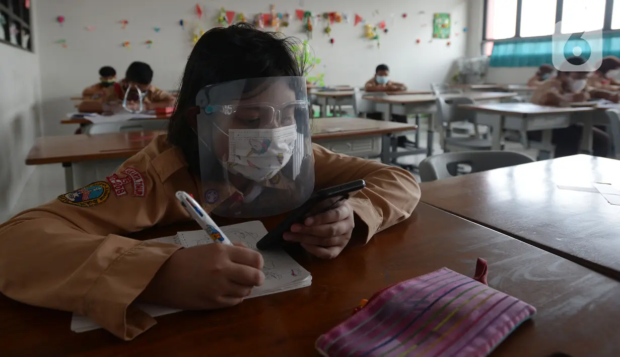Seorang murid memakai masker dan pelindung wajah saat mengikuti uji coba pembelajaran tatap muka di SDN Malaka Jaya 07 Jakarta, Rabu (9/6/2021). Pembelajaran dilakukan secara campuran antara online (daring) dan tatap muka langsung. (merdeka.com/Imam Buhori)