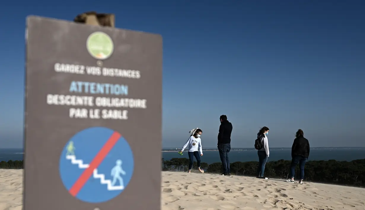 Orang-orang menikmati hari yang cerah di atas gundukan pasir tertinggi di Eropa yang disebut "Dune du Pilat" di La Teste-de-Buch, Prancis pada 3 April 2021. The Dune of Pilat memiliki keunikan, yakni bukitnya dapat bergerak hingga mencapai 4,9 meter per tahunnya. (Philippe LOPEZ / AFP)