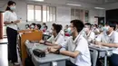 Para siswa mendengarkan guru pada hari pertama semester baru di Wuhan, Provinsi Hubei, China, 1 September 2021. Pemerintah China memutuskan pemberlakuan belajar tatap muka setelah percaya diri menangani pandemi COVID-19. (STR/AFP)