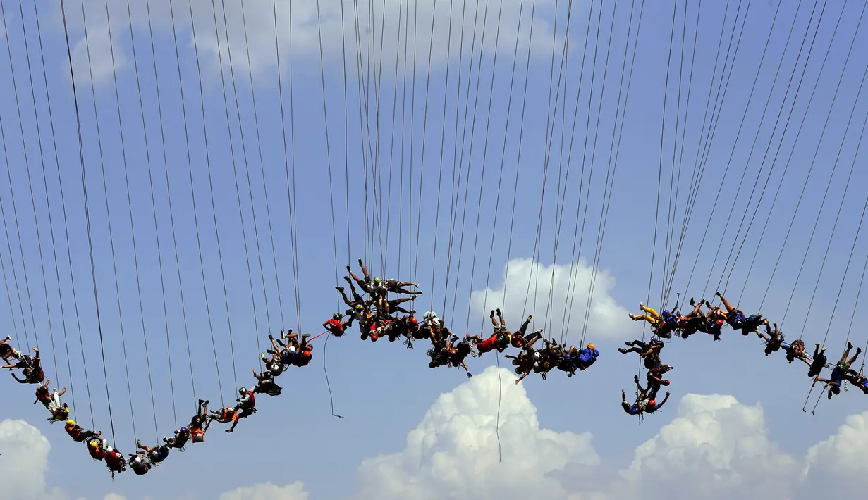 Ratusan orang bergelantung di jembatan yang memiliki ketinggian 30 meter di Hortolandia, Brasil, Minggu (10/4). Sebanyak 149 orang mencoba membuat rekor dunia dengan melompat bersama dari atas jembatan. (REUTERS/Paulo Whitaker)