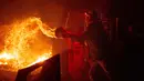 Salah satu warga, Francis Lopez berjuang memadamkan api dengan seember air saat kebakaran hutan membakar lahan miliknya di Aguanga, California, Senin, 30 Oktober 2023. (AP Photo/Ethan Swope)
