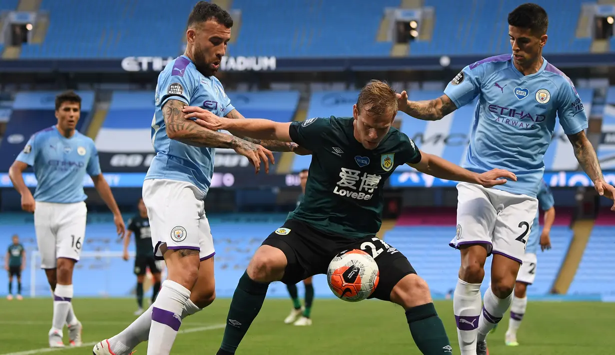 Penyerang Burnley, Matej Vydra (tengah) berusaha mengontrol bola dari kawalan dua pemain Manchester City, Nicolas Otamendi dan Riyad Mahrez pada pertandingan lanjutan Liga Inggris di Stadion Etihad di Manchester, Inggris (22/6/2020). City menang telak 5-0 atas Burnley. (Michael Regan/POOL/AFP)