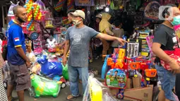 Warga memilih mainan tanpa menjaga jarak di Pasar Gembrong, Jakarta Timur, Minggu (31/5/2020). Meski penerapan masa Pembatasan Sosial Berskala Besar (PSBB) di Jakarta masih berlaku, namun pasar yang khusus menjual pernak-pernik mainan anak ini kembali dipadati warga. (Liputan6.com/Immanuel Antonius)