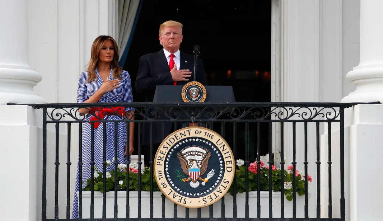Presiden Donald Trump dan Ibu Negara AS, Melania saat menyanyikan lagu kebangsaan pada acara piknik merayakan Hari Kemerdekaan di halaman Gedung Putih, Rabu (4/7). Trump menggelar acara piknik untuk menjamu keluarga-keluarga militer. (AP/Alex Brandon)