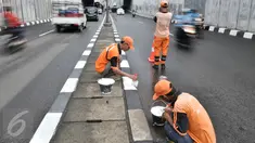 Sejumlah Petugas Pengelolaan Prasarana dan Sarana Umum (PPSU) mengecat pembatas jalan di Jalan Raya Pasar Minggu, Jakarta, Senin (27/2). Pengecatan dilakukan karena warna cat trotoar dan pembatas jalan sudah pudar. (Liputan6.com/Yoppy Renato)