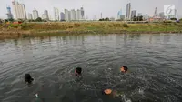 Anak-anak berenang di Kanal Banjir Barat (KBB) yang hitam di Petamburan, Jakarta, Senin (12/8/2019). Surutnya debit air KBB akibat musim kemarau dimanfaatkan anak-anak untuk bermain sambil mencari ikan. (Liputan6.com/Fery Pradolo)
