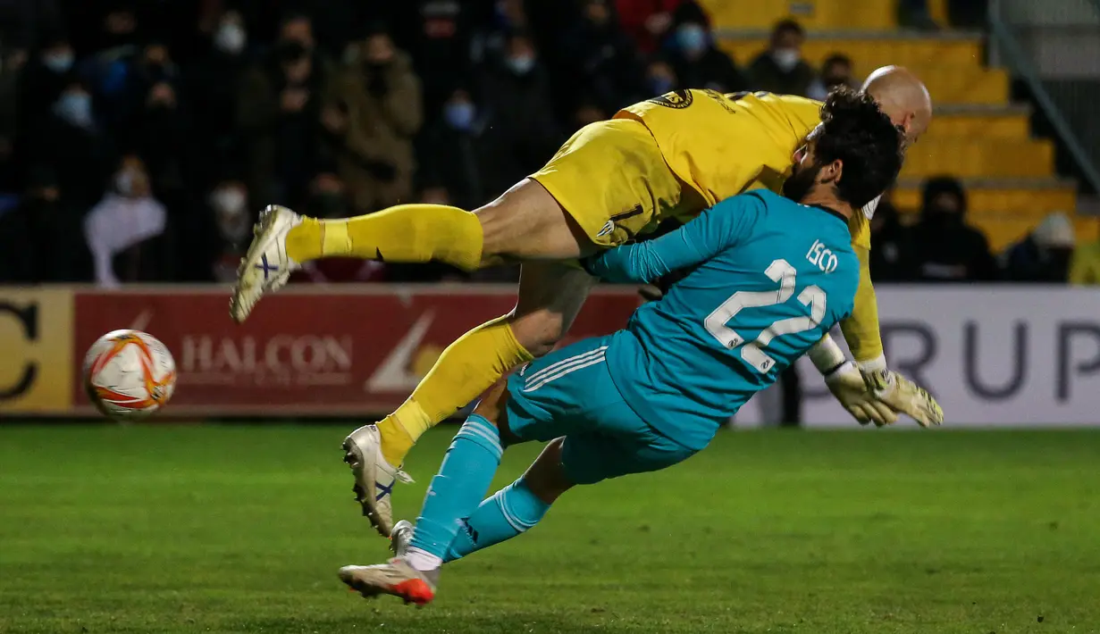 Kiper Alcoyano, Jose Juan (Atas) berebut bola dengan gelandang Real Madrid Isco pada babak 32 besar Copa del Rey di Stadion El Callao, Alcoy, Kamis (6/1/2022) dini hari WIB. Real Madrid mengalahkan tim divis tiga Spanyol, Alcoyano dengan skor 3-1. (JOSE JORDAN / AFP)