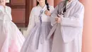 Ia mengenakan hanbok pastel putih ungu dengan rambut half ponytail berhiaskan untaian bunga [@hestipurwadinata]