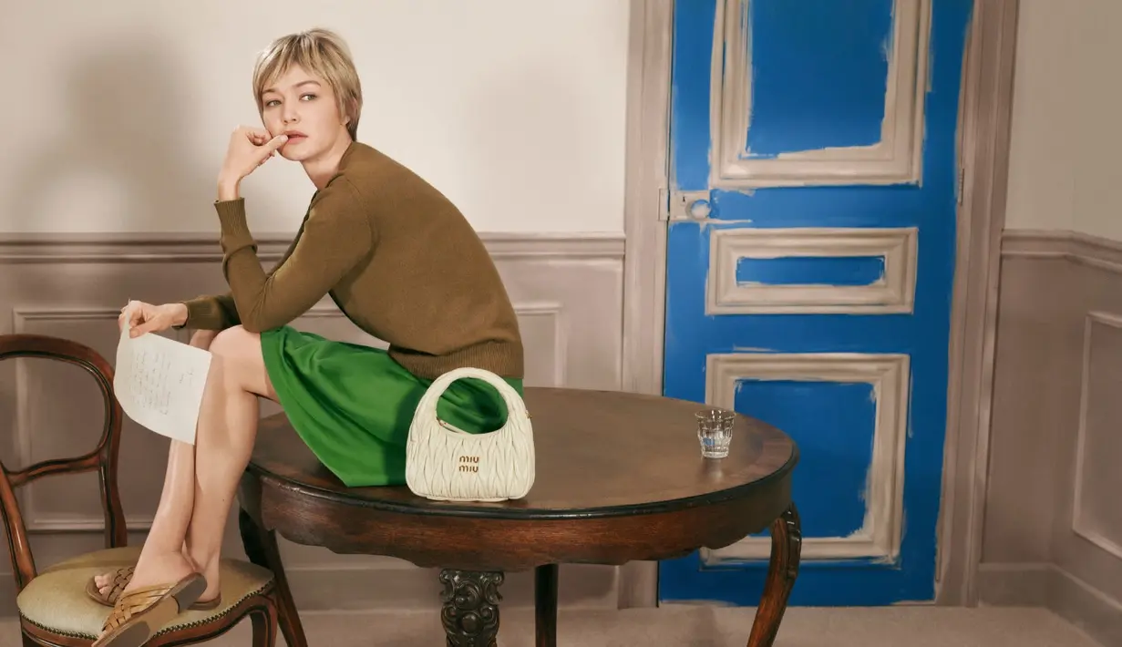 Dalam salah satu tampilannya, Gigi mengenakan crop knit top biru elektrik dengan rok hitam high-waist dan tas hijau Miu Miu matelassé yang menjadi statement utama. [Dok/Miu Miu].