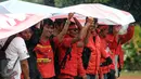 Buruh berteduh di bawah bentangan spanduk saat aksi di lapangan DitSabhara Polda Metro Jaya, Jakarta, Rabu (17/2/2016). Dalam aksinya, mereka meminta pencabutan status tersangka pada 26 orang buruh aktivis. (Liputan6.com/Helmi Fithriansyah)