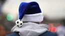  Seorang Fan dengan topi Sinterklas berwarna biru dan bola kecil bersiap menyaksikan laga Premier League antara  West Bromwich Albion v Watford, (3/12/2016).  (Reuters/Anthony Devlin)