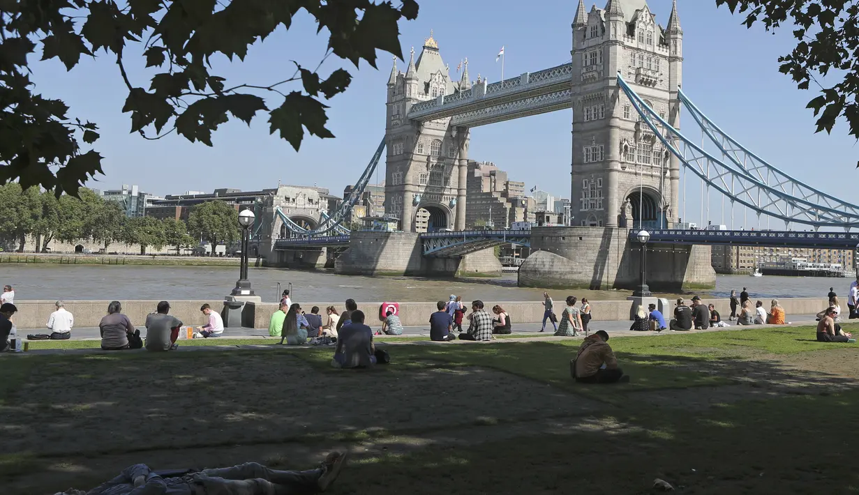 Seorang pria tidur di bawah naungan pohon di rumput dekat Potters Field menghadap Tower Bridge saat suhu mendekati 30 derajat celsius di London, Selasa (7/9/2021).  (AP Photo/Tony Hicks)