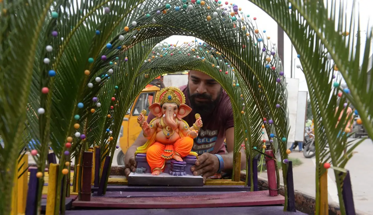 Seorang perajin memajang patung Dewa Ganesha untuk dijual di kios pinggir jalan di Hyderabad, India, Kamis (9/9/2021). Patung dewa Hindu berkepala gajah tersebut banyak dijual jelang Festival Ganesh Chaturthi. (NOAH SEELAM/AFP)