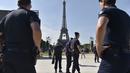 Sejumlah polisi melakukan penjagaan jelang acara Champs de Mars yang digelar untuk menyambut Piala Eropa 2016 di Paris fan zone, belakang Menara Eiffel, Prancis, Jumat (10/6/2016). (AFP/Alain Jocard)