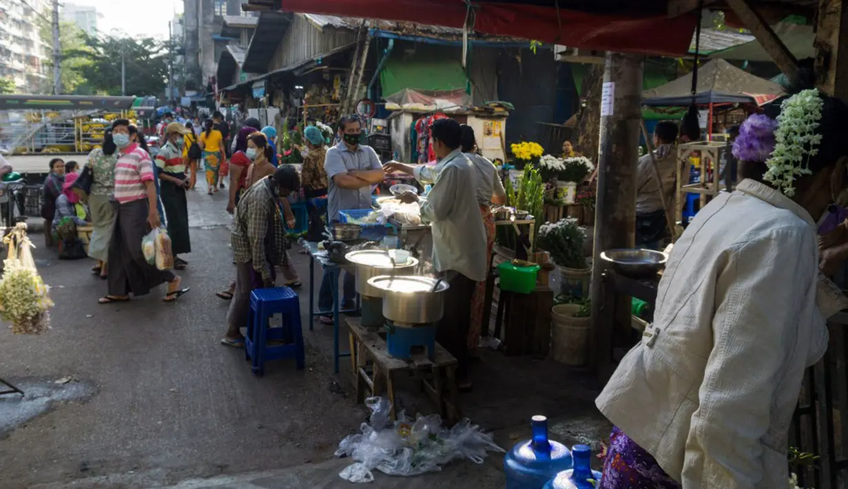 Orang-orang membeli makanan di sebuah pasar sehari setelah militer Myanmar merebut kekuasaan, Yangon, Myanmar, Selasa (2/2/2021). Militer Myanmar menahan pemimpin yang terpilih secara demokratis Aung San Suu Kyi dan memberlakukan keadaan darurat satu tahun. (STR/AFP)