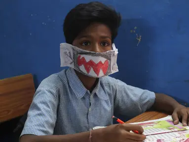 Seorang siswa India mengenakan masker buatannya sendiri saat mendengarkan seorang guru di sebuah sekolah pemerintah di Hyderabad, India, Rabu (4/3/2020). Menurut informasi yang beredar masker tersebut dibuat menggunakan kertas dan di gambar. (AP Photo/Mahesh Kumar A.)