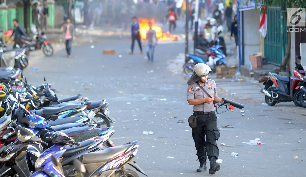 Petugas kepolisian mengecek senjata gas air mata saat bentrok dengan massa aksi di kawasan Slipi, Jakarta, Rabu (22/5/2019). Jalan tol dalam kota sempat ditutup sekitar setengah jam, dan massa dihalau petugas ke arah kemanggisan. (merdeka.com/Arie Basuki)