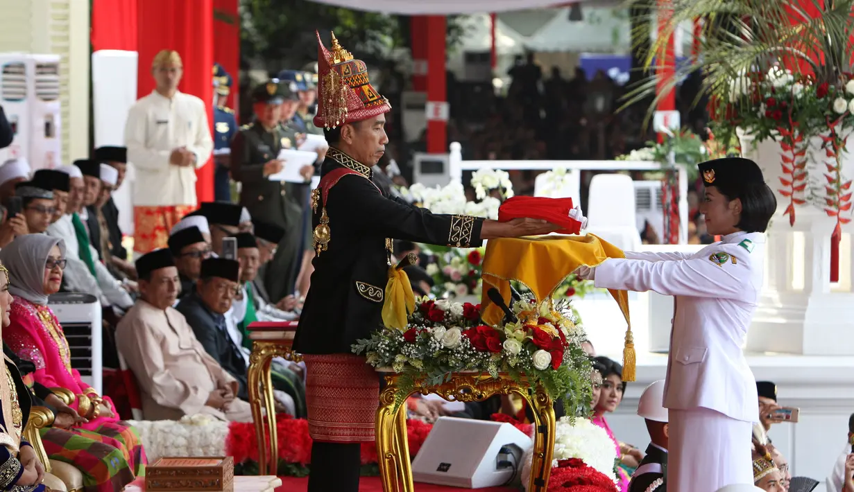 Presiden Joko Widodo (tengah) menyerahkan duplikat bendera pusaka kepada Paskibraka Tarrisa Maharani Dewi saat Upacara Peringatan Detik-detik Proklamasi Kemerdekaan ke-73 di Istana Merdeka, Jakarta, Jumat (17/8). (Liputan6.com/HO/Bian)