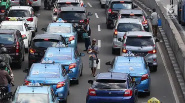 Pedagang asongan menjajakan barang dagangannya di persimpangan lampu merah di Jakarta, Jumat (22/2). Keahlian yang terbatas menyebabkan sebagian orang harus bekerja di tengah padatnya kendaraan Ibukota. (Liputan6.com/Immanuel Antonius)