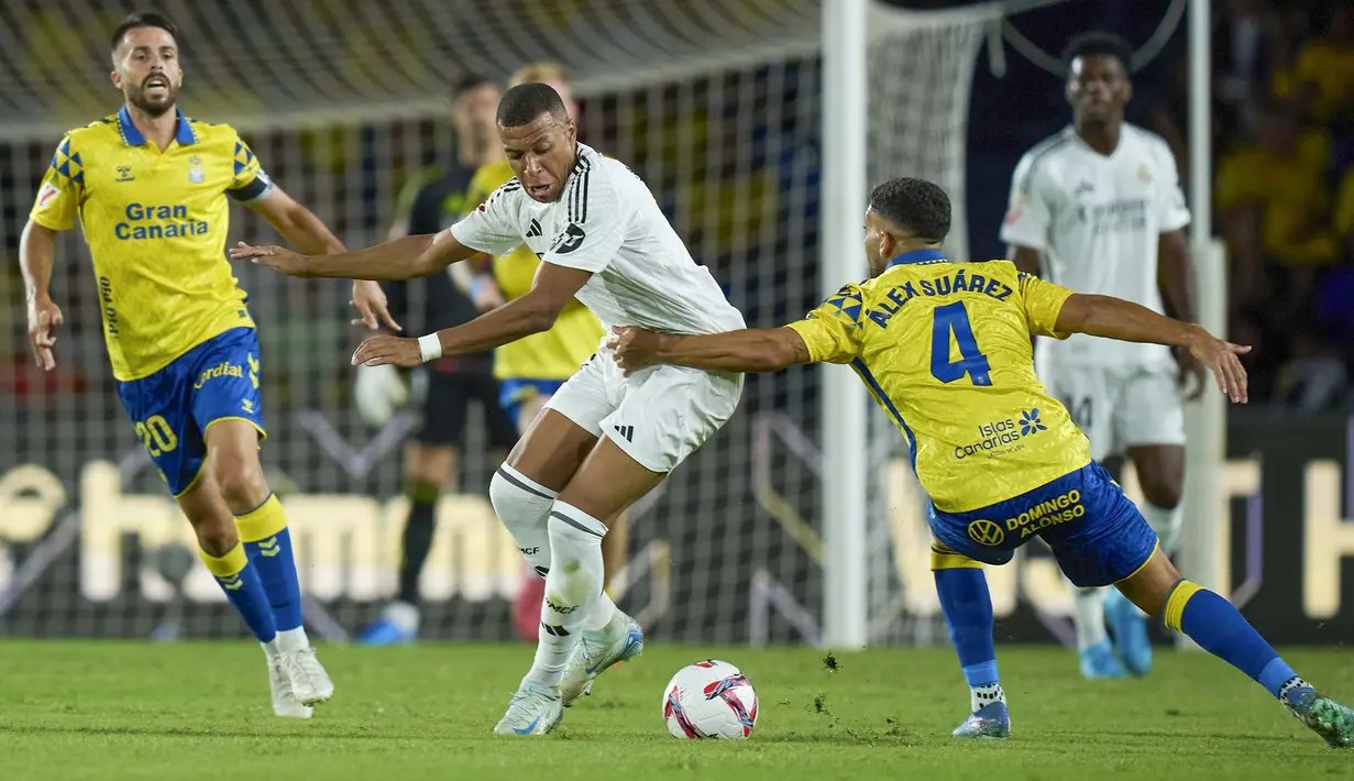 Pemain Real Madrid, Kylian Mbappe, berebut bola dengan pemain Las Palmas, Alex Suarez, pada laga pekan ketiga La Liga 2024/2025 di Stadion Gran Canaria, Jumat (30/8/2024).  (AP Photo/Gabriel Jimenez)