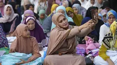 Seorang perempuan berswafoto sebelum sholat Idul Adha di sebuah jalan di Jakarta, Indonesia, Kamis, 29 Juni 2023. (AP Photo/Tatan Syuflana)