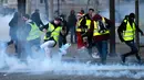 Demonstran menendang tabung gas air mata saat kerusuhan menentang kenaikan harga bahan bakar di Paris, Prancis, Sabtu (24/11). Polisi menggunakan gas air mata dan meriam air untuk membubarkan demonstran. (AP Photo/Christophe Ena)