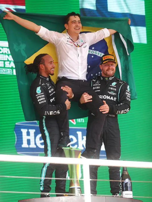 Pembalap Mercedes Lewis Hamilton (kiri) dan pembalap Mercedes Valtteri Bottas (kanan) memegang seorang engineer tim di pundak mereka saat merayakan posisi pertama dan ketiga pada Formula 1 Grand Prix di Sirkuit Interlagos, Sao Paulo, Brasil, 14 November 2021. (Lars Baron, Pool Photo via AP)