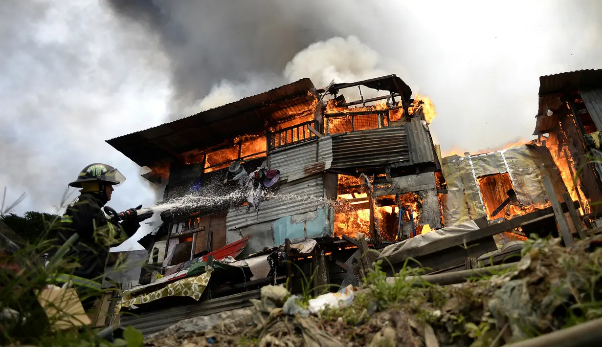 Petugas pemadam kebakaran berusaha memadamkan api yang membakar kawasan kumuh di Manila, Filipina (11/8). Sejauh ini kebakaran menghancurkan 300 rumah dan mengakibatkan 800 keluarga harus dievakuasi. (AFP Photo/Noel Celis)