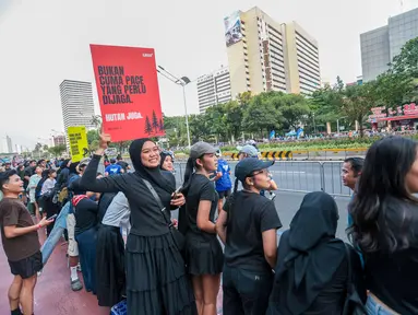 Seorang penonton membawa poster bertema kebakaran hutan dan lahan (karhutla) saat Jakarta Running Festival (JRF) 2026 di sepanjang lintasan Jalan Jenderal Sudirman, Jakarta, Sabtu (24/10/2026). (KLY/Budy Santoso)