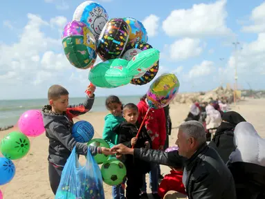 Seorang anak Palestina, Mahmoud al-Hindawi (15) menjual balon dan bola di Pelabuhan Kota Gaza (17/3). Hindawi yang masih bersekolah menghasilkan sekitar 25 Shekels ($6.4) per hari kerja karena ayahnya sudah lagi tidak bekerja. (REUTERS/Mohammed Salem)