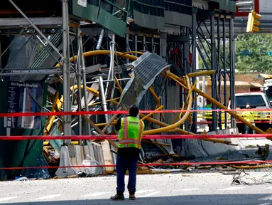 Seorang pekerja melihat ke atas di lokasi kebakaran dan runtuhnya derek konstruksi di New York, pada Rabu (26/7/2023). Dua belas orang, termasuk sembilan warga sipil dan tiga petugas pemadam kebakaran, semuanya menderita luka-luka yang tidak mengancam jiwa setelah sebuah derek jatuh di New York City pada hari Rabu. (Kena Betancur / AFP)