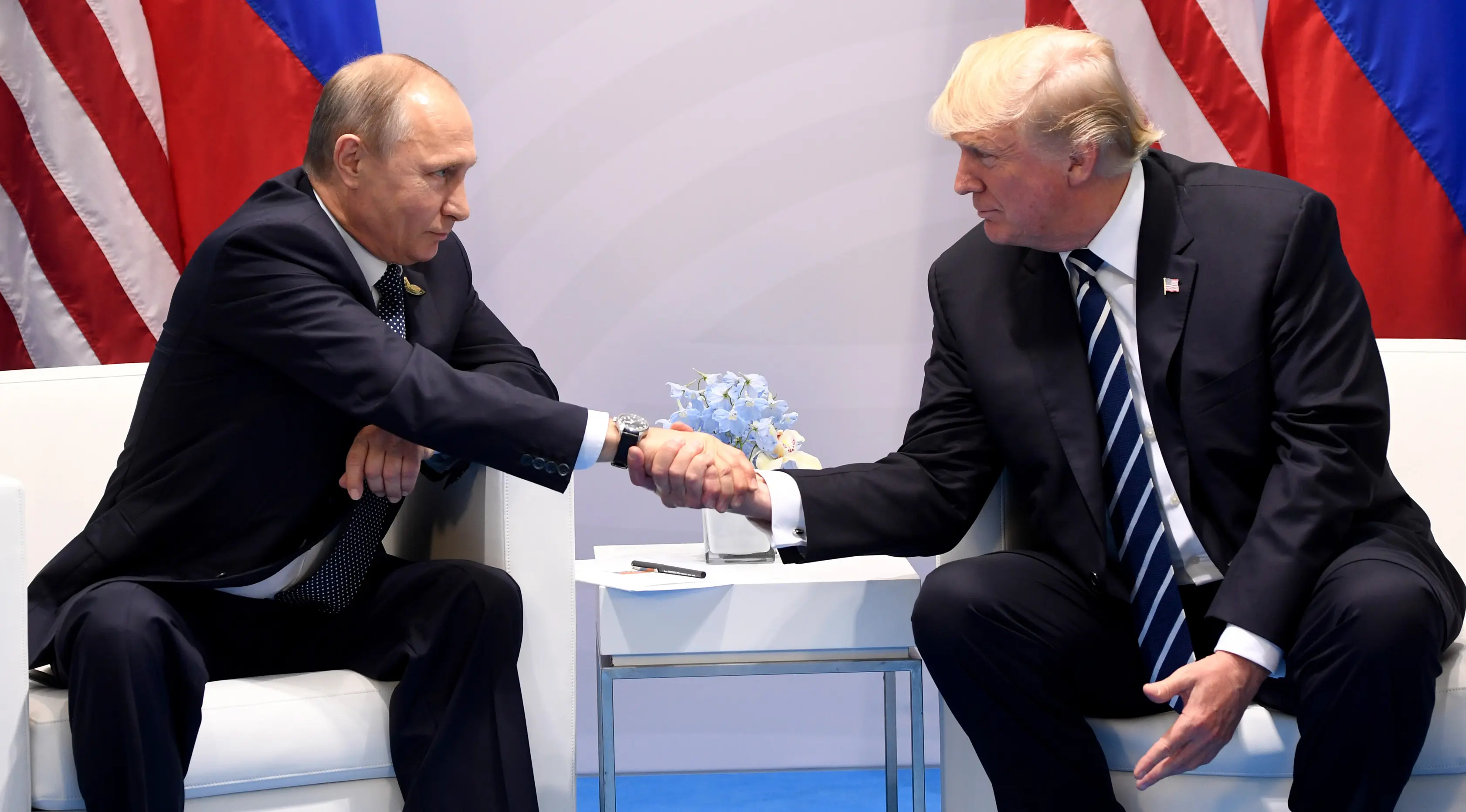 Presiden AS, Donald Trump (kanan) bersalaman dengan Presiden Rusia Vladimir Putin saat bertemu di KTT G20, di Hamburg, Jerman (7/7). Kedua pemimpin iini bertemu selama setengah hingga satu jam. (AFP Photo/Soul Loeb)