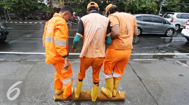 Petugas Dinas Kebersihan mengeluarkan air dari busa di Harmoni, Jakarta, Selasa (9/2). Buruknya sistem drainase membuat petugas terpaksa harus membersihkan genangan setiap kali hujan, meski dengan peralatan seadanya. (Liputan6.com/Immanuel Antonius)