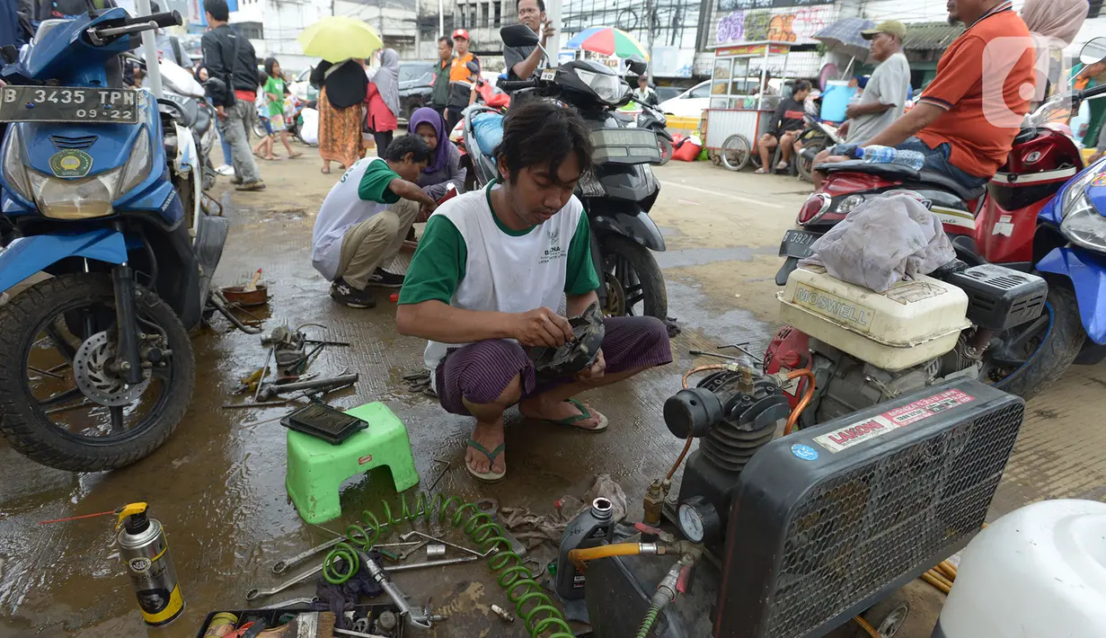 Para montir memperbaiki sepeda motor korban banjir pada layanan bengkel gratis Badan Amil Zakat Nasional (BAZNAS) di Kampung Pulo, Jakarta, Sabtu (4/1/2020). Layanan bengkel gratis ini banyak dimanfaatkan korban banjir untuk memperbaiki sepeda motornya yang sempat terendam. (merdeka.com/Imam Buhori)