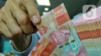 Pegawai menata mata uang rupiah di salah satu gerai penukaran mata uang di Jakarta, Kamis (5/1/2023). Nilai tukar rupiah ditutup di level Rp15.616 per dolar AS pada Kamis (5/1) sore ini. Mata uang Garuda melemah 34 poin atau minus 0,22 persen dari perdagangan sebelumnya. (Liputan6.com/Angga Yuniar)