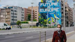 Seorang pria yang mengenakan masker melewati sebuah jalan di Brussel, Belgia, Selasa (7/7/2020). Komisi Eropa memprediksi Ekonomi Eropa akan menghadapi resesi lebih dalam akibat langkah-langkah pengendalian COVID-19 yang berkepanjangan. (Xinhua/Zhang Cheng)