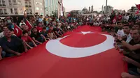 Bendera nasional Turki berukuran besar dibentangkan pendukung Presiden Turki, Tayyip Erdogan di Taksim Square, pusat kota Istanbul, Sabtu (16/7). Ratusan warga turun ke jalan untuk merayakan kegagalan kudeta militer di Turki. (REUTERS/Huseyin Aldemir)