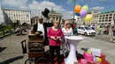 Keberadaan patung lilin Angela Merkel, di depan gerbang Brandenburg di Berlin, (16/7/2014), mengundang minat wisatawan untuk berpose di samping replika Kanselir Jerman. (AFP PHOTO/Clemens Bilan)