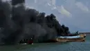 Asap hitam mengepul dari kapal asing ilegal asal Malaysia yang dibakar dan ditenggelamkan Kejaksaan Negeri Banda Aceh di perairan Pelabuhan Perikanan Samudera Kutaraja, Banda Aceh, Aceh, Kamis (18/3/2021). (AFP/Chaideer Mahyuddin)