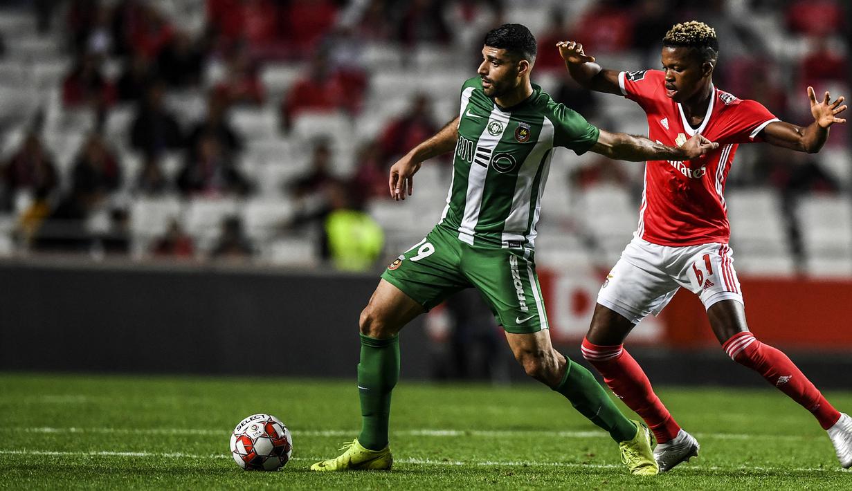 Striker Rio Ave, Mehdi Taremi (kiri) menguasai bola dibayangi gelandang Benfica, Florentino Luis dalam laga Primeira Liga 2019/2020 di Da Luz Stadium, Lisbon (2/11/2019). Pemain asal Iran berusia 30 tahun yang sejak awal musim 2020/2021 memperkuat FC Porto ini pernah menjadi top skor di Liga Portugal (Primeira Liga) dengan torehan 18 gol pada musim 2019/2020 saat membela Rio Ave. (AFP/Patricia De Melo Moreira)