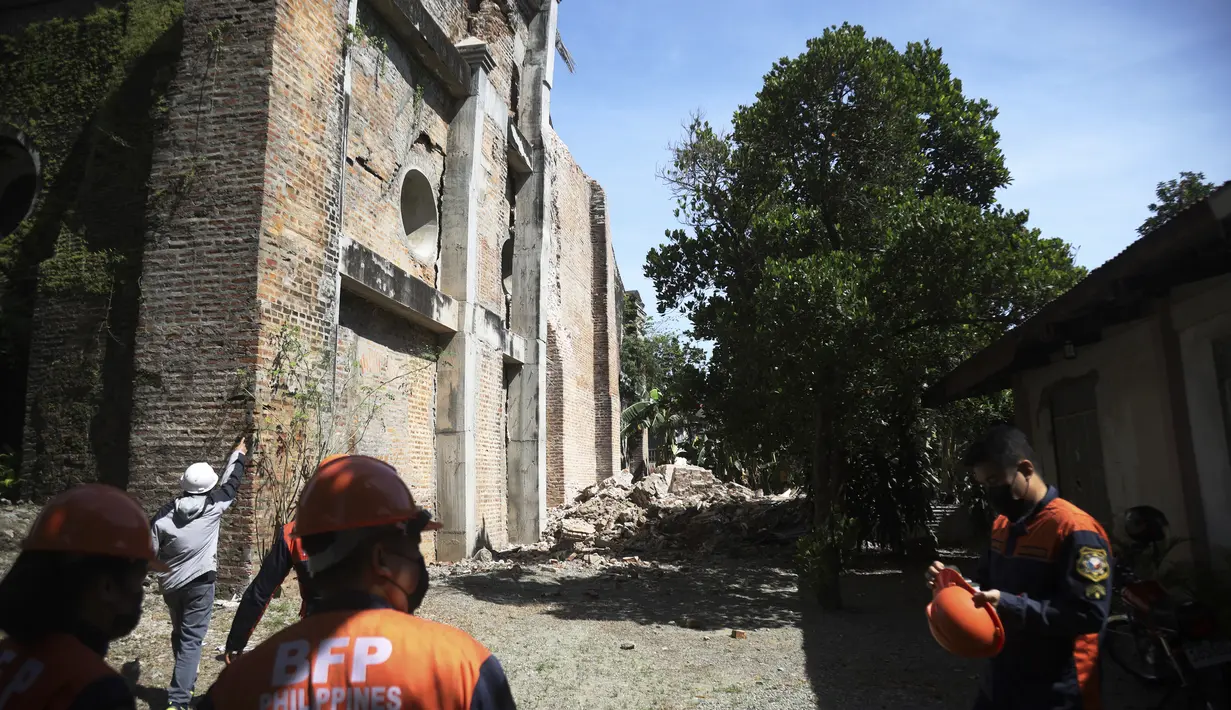 Petugas pemadam kebakaran berdiri di samping gereja yang rusak setelah gempa kuat di Ilocos Norte, Filipina Utara, Rabu (26/10/2022). Gempa kuat mengguncang sebagian besar Filipina utara, melukai banyak orang dan memaksa penutupan bandara internasional dan bandara. evakuasi pasien di rumah sakit. (AP Photo)
