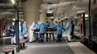 Petugas medis membawa pasien virus corona COVID-19 di Stasiun Gare d'Austerlitz di Paris, Prancis, Rabu (1/4/2020). Pasien COVID-19 dievakuasi menggunakan kereta kecepatan tinggi dari rumah sakit di Paris ke rumah sakit di Brittany dimana kasus tersebut masih terbatas. (Thomas SAMSON/AFP/POOL)