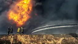 Petugas pemadam kebakaran saat berusahan memadamkan api di salah satu tangki minyak yang terbakar di pelabuhan Es Sider, Libya, (6.1).  Diduga penyebab kebakaran adalah serangan yang dilakukan oleh kelompok militan. (REUTERS / Stringer)