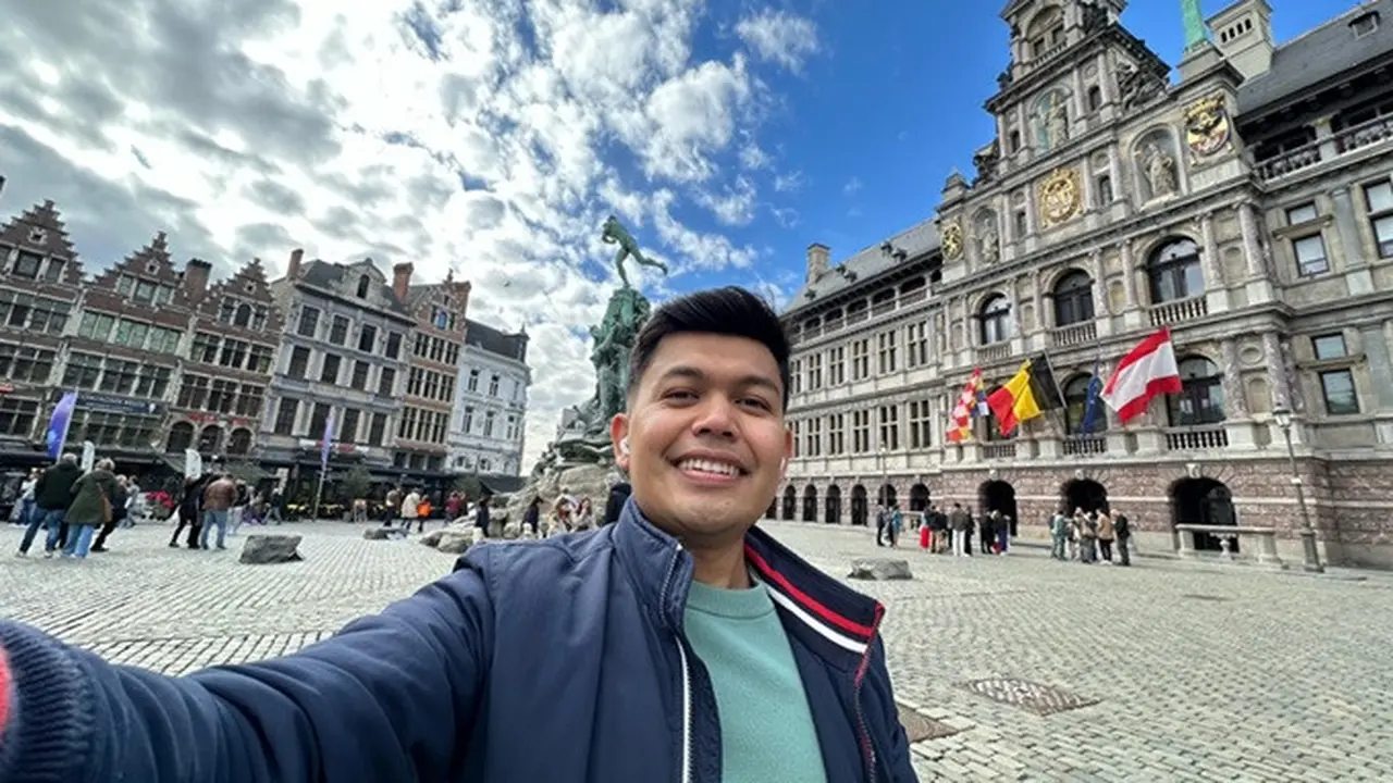WNI bernama Aris Munandar saat berada di Grote Markt, dengan latar belakang Stad Huis (City Hall). Di depan Stad Huis ada patung Silvius Brabo yang menjadi ikon Kota Antwerp.