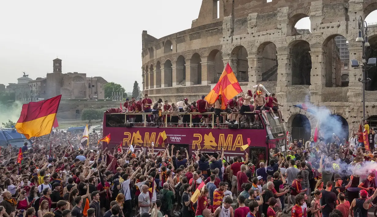 Suporter AS Roma bergembira saat bus membawa pemain AS Roma merayakan kemenangan juara Liga Konferensi Eropa UECL di depan Colosseum di Roma (26/5/2022). AS Roma menjuarai Konferensi Eropa UECL setelah mengalahkan Fayenoord dengan skor tipis 1-0. (AP Photo/Gregorio Borgia)